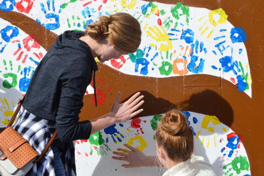 Two Grand Valley students place their hand prints on the KIC mural.